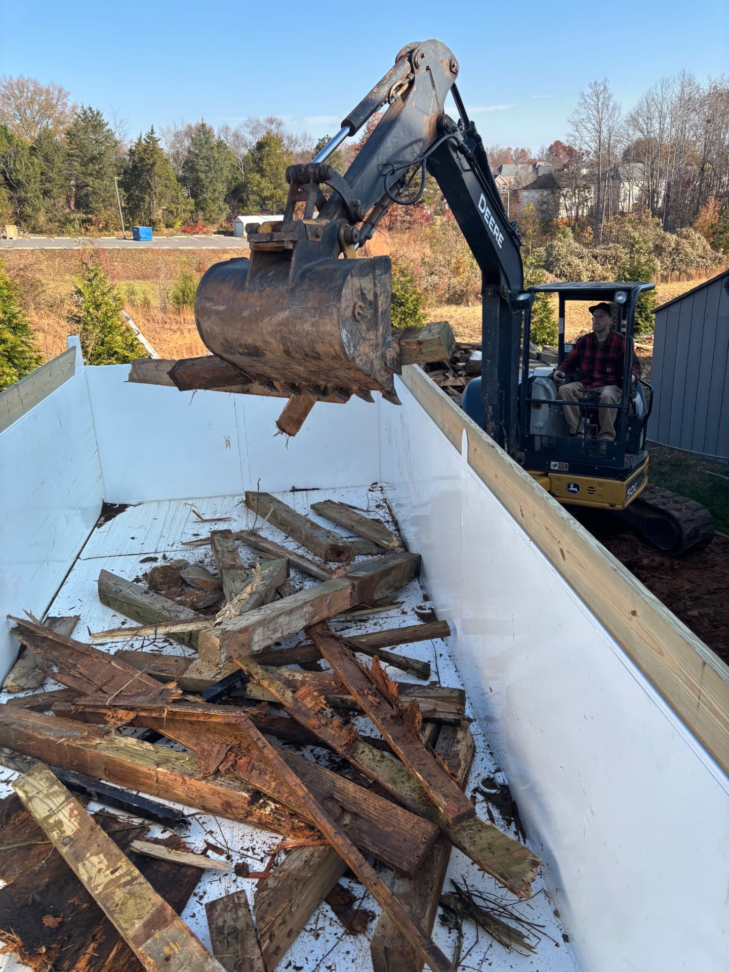 Excavator loading demolition debris into a dump trailer