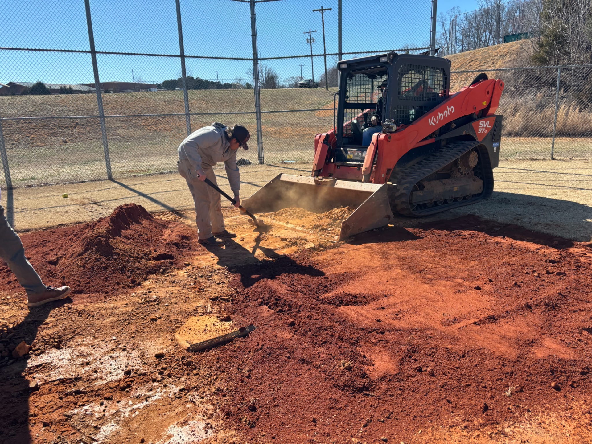 Track loader and crew regrading a ballfield home plate